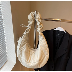Detail of beige quilted crescent bag with ruffled strap and stylish side drawstring