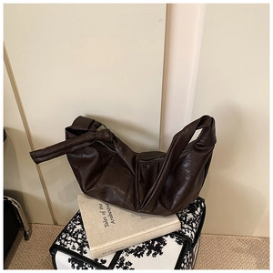 Detail view of the side knot and soft pleated leather texture of this dark brown hobo bag