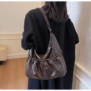 Detailansicht der kaffeebraunen Crescent-Tasche mit Falten-Design getragen am Modell