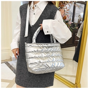 Close-up of a silver quilted tote bag featuring a glossy metallic finish and wide shoulder strap