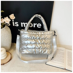 Detail view of silver quilted puffer bag with nylon shoulder strap and metallic finish