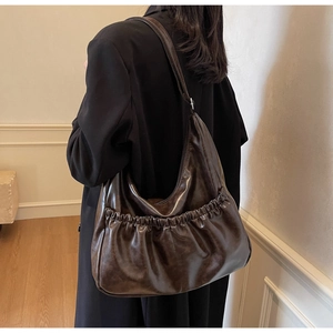 Detail der dunkelbraunen Hobo-Tasche mit gefalteten Taschen und glänzendem Finish