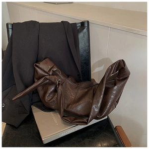 Close-up of vintage brown leather hobo bag with pleated texture and knotted shoulder strap