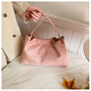 Detail of soft pink faux suede Boston bag with gold metal rings and long shoulder strap