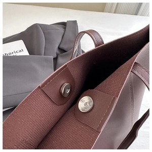 Close-up of brown tote bag with magnetic clasp closure and premium leather texture