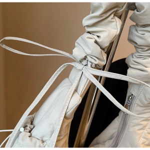 Detailed close-up of beige down bag featuring drawstring accents and silver metal zipper