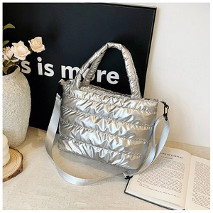 Close-up of metallic silver quilted tote bag with padded texture and wide shoulder strap
