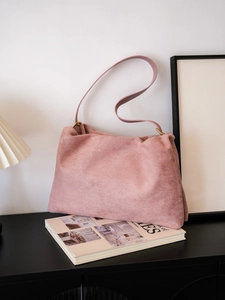 Detail of a soft pink faux suede Boston bag with golden metal buckles and slim shoulder strap