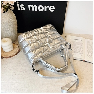 Detail of silver quilted puffer tote bag showing metallic texture and detachable strap