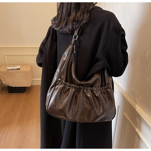 Detailansicht der plissierten Hobo-Tasche mit verstellbarem Gurt in Dunkelbraun