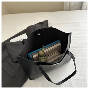 Detail view of spacious black tote bag interior showing capacity for tablet and daily items