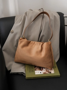 Detail shot of brown suede Boston bag on a grey blazer showing soft matte texture