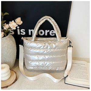 Detailed macro view showing the metallic quilted texture and zipper of the silver tote bag