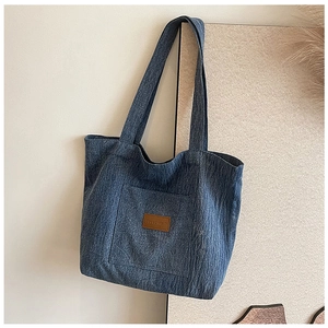 Close-up of blue denim tote bag featuring a brown leather patch and woven handles