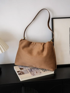 Detailed close-up of brown suede Boston bag featuring elegant golden metal rings and leather strap