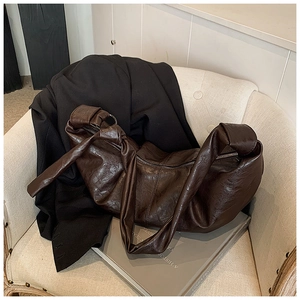 Detail of soft brown leather shoulder bag featuring knotted strap and pleated texture