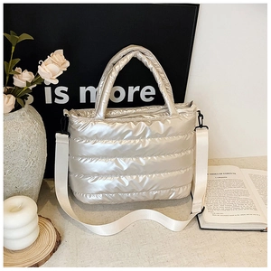 Close-up of shiny silver quilted tote bag with metallic texture and white shoulder strap