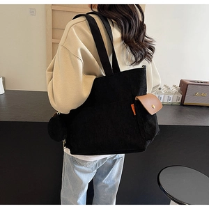 Detail view of large black corduroy tote bag with side leather pocket and small round coin purse