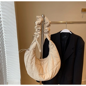 Detail of beige quilted crescent bag with puffy cloud strap on display