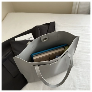 Macro shot showing large gray tote bag interior with tablet, books, and magnetic closure