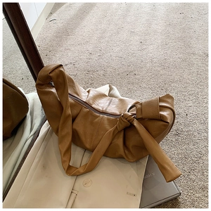 Detailed close-up of a brown pleated crescent bag featuring knotted straps and soft leather