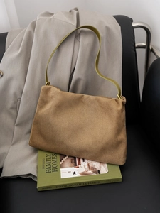 Detailed macro view of the brown suede surface and green leather strap of the Boston bag