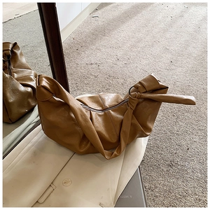 Detail of vintage brown crescent bag showing soft pleated texture and side knot strap