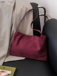 Macro detail of high-quality burgundy suede Boston bag on a luxury leather surface