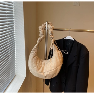 Detailed close-up of beige quilted puffy shoulder bag with ruched strap detail
