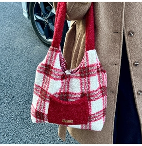 Detailed macro view of the red plush tote bag featuring a golden metal logo on the front pocket