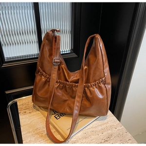 Detail einer braunen plissierten Ledertasche mit verstellbarer silberner Schnalle