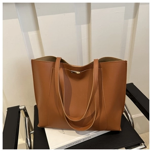 Macro view of tan matte faux leather tote bag with elegant gold metal bar accent