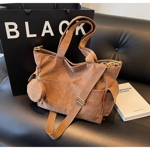 Brown corduroy tote bag detail with adjustable shoulder strap and small charm pouch