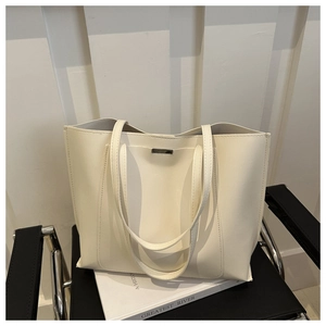 Close-up of minimalist cream tote bag with fine metal trim on a stylish chair
