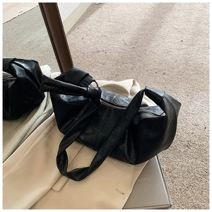 Close-up of black pleated PU leather bag with knotted handle and silver metal zipper detail