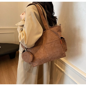 Detail view of brown corduroy tote bag with side pocket and round zipper pendant