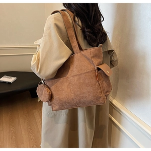 Detail of dark brown corduroy tote bag showing soft ribbed texture and side flap pocket