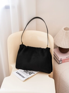 Detailed close-up of a black suede Boston bag featuring elegant gold hardware on a chair