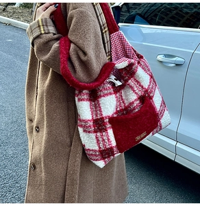 Detail view of red plaid plush tote bag with fuzzy handles and small brand patch