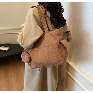 Macro shot of brown corduroy tote bag with side pocket and round coin purse attachment