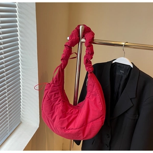 Detail of fuchsia quilted down dumpling bag with ruched handle and puffer texture