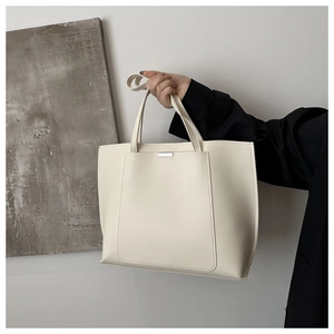 Detail of a large cream tote bag showing clear PU leather texture and silver metal buckle