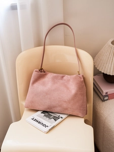 Detail of vintage pink Boston bag in soft suede leather on a cream chair setup