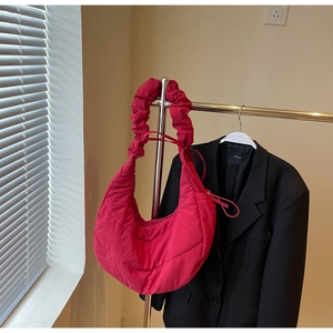 Detail of fuchsia puffer crescent bag featuring ruched shoulder strap and quilted texture