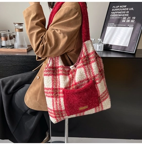 Detail view of red plaid plush tote bag with Our Love metal logo on external pocket