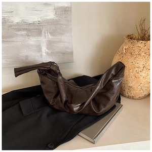 Detailed view of dark brown pleated leather shoulder bag with decorative knotted handle