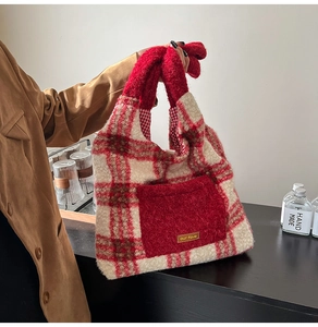 Close-up of red and white plaid plush tote bag with furry pocket and gold label detail