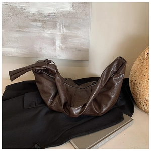 Detail of vintage pleated dark brown leather shoulder bag with knot strap and zipper