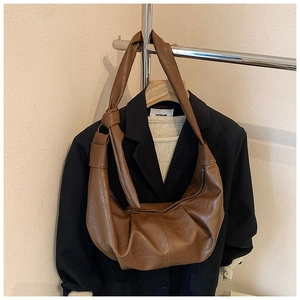 Close-up of brown crescent moon bag with soft pleated leather and knotted shoulder strap