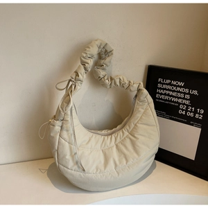 Detail of a cream quilted hobo bag featuring a pleated handle and fluffy puffed texture